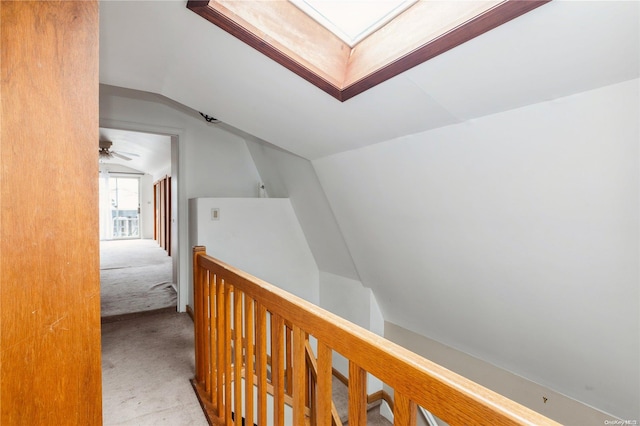 corridor featuring vaulted ceiling with skylight and light colored carpet