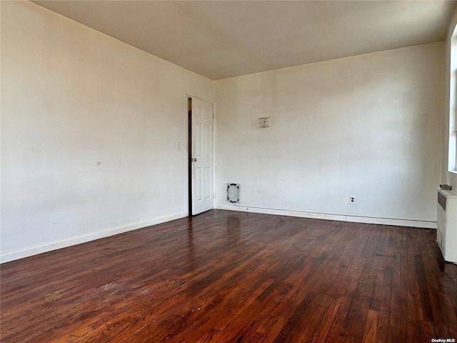 empty room with radiator heating unit and dark wood-type flooring