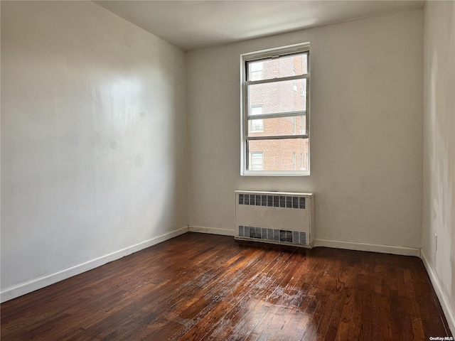 empty room with radiator heating unit and dark hardwood / wood-style floors