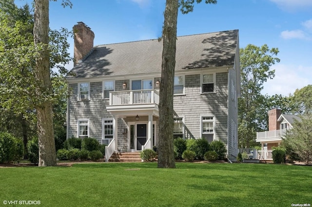 view of front of house with a balcony and a front lawn