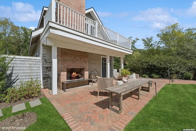 view of patio featuring a balcony and an outdoor brick fireplace