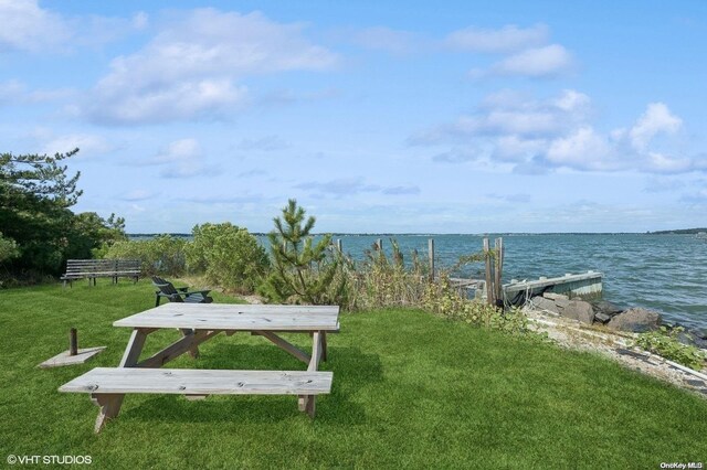 view of property's community with a boat dock, a water view, and a yard