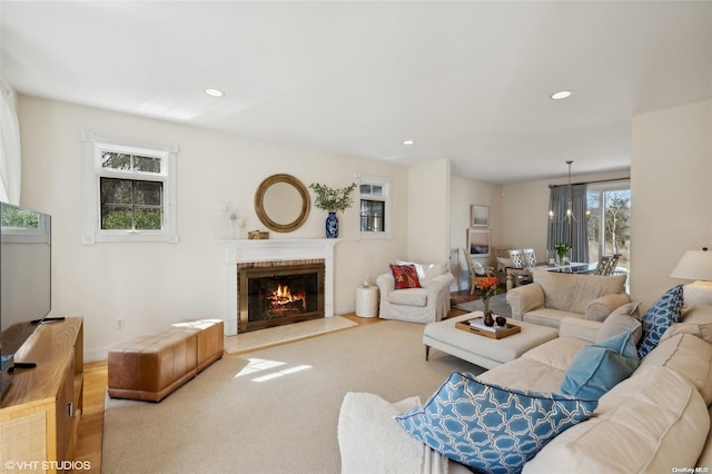 living room featuring a fireplace, light carpet, and a chandelier