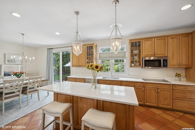 kitchen featuring tile patterned floors, a kitchen breakfast bar, stovetop, and sink