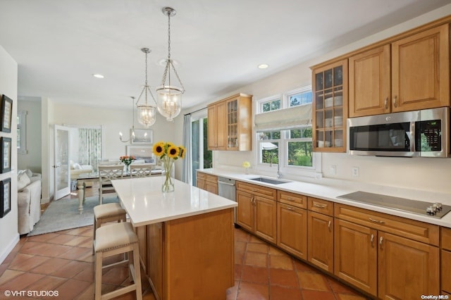 kitchen with sink, decorative light fixtures, a breakfast bar, a kitchen island, and appliances with stainless steel finishes