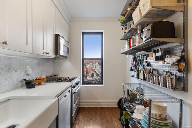 kitchen with dark hardwood / wood-style floors, decorative backsplash, ornamental molding, appliances with stainless steel finishes, and white cabinetry