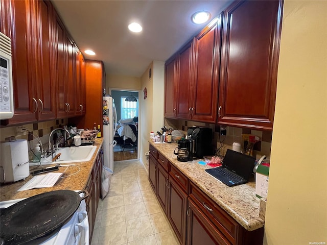 kitchen with backsplash, light tile patterned flooring, light stone countertops, and sink