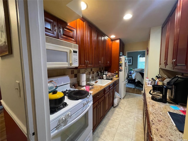 kitchen featuring light stone countertops, light tile patterned floors, white appliances, and sink