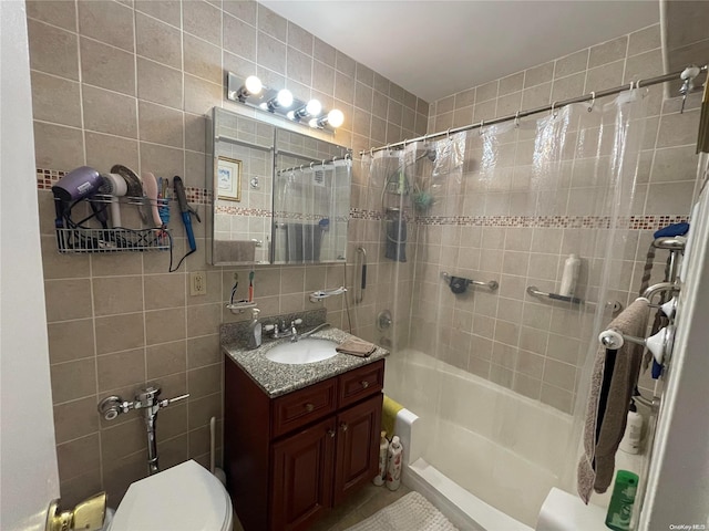 full bathroom featuring vanity, shower / bathtub combination with curtain, toilet, and tile walls