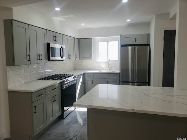 kitchen featuring gray cabinets, light stone countertops, sink, and stainless steel appliances