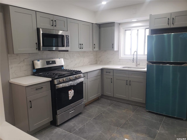 kitchen featuring tasteful backsplash, gray cabinets, sink, and stainless steel appliances