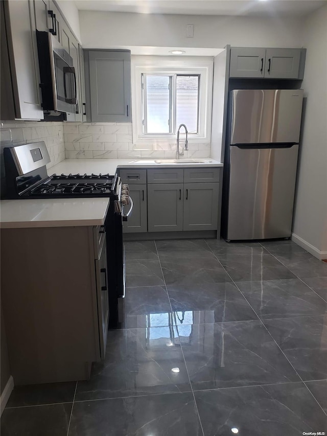 kitchen with tasteful backsplash, gray cabinets, sink, and stainless steel appliances