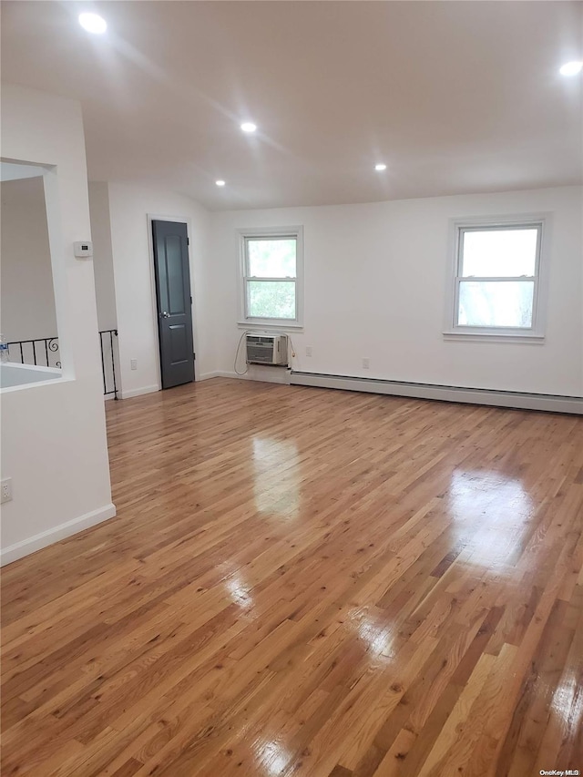 empty room featuring a wall mounted AC, a baseboard heating unit, and light wood-type flooring