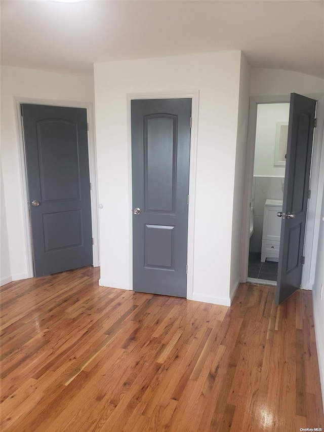 unfurnished bedroom featuring light hardwood / wood-style floors and connected bathroom