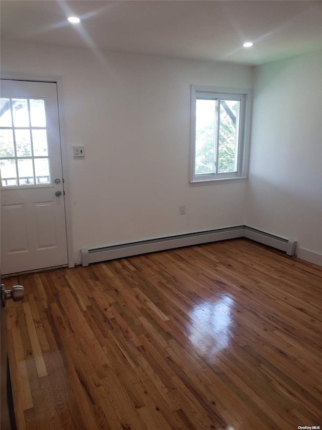 interior space featuring dark wood-type flooring, a baseboard radiator, and a healthy amount of sunlight