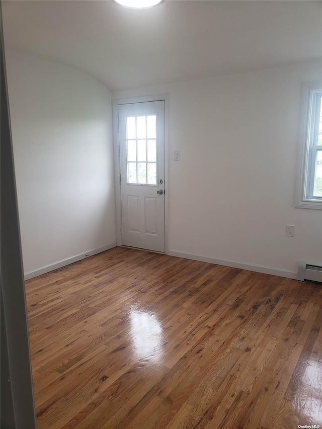 spare room featuring hardwood / wood-style floors, a wealth of natural light, and a baseboard radiator