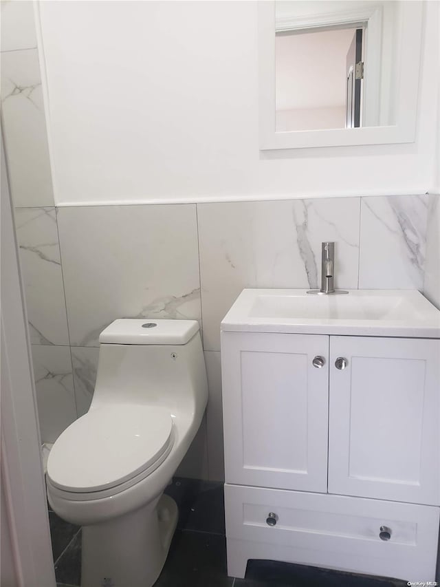 bathroom with vanity, toilet, and tile walls