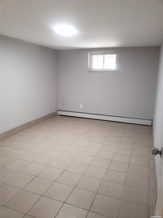 empty room featuring baseboard heating and light tile patterned floors