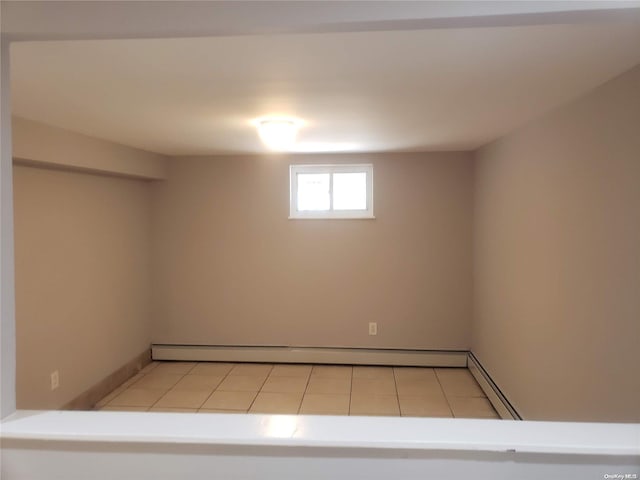 basement featuring a baseboard heating unit and light tile patterned flooring