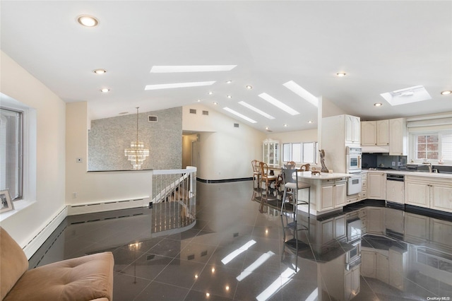 kitchen with kitchen peninsula, a kitchen breakfast bar, lofted ceiling with skylight, double oven, and decorative light fixtures