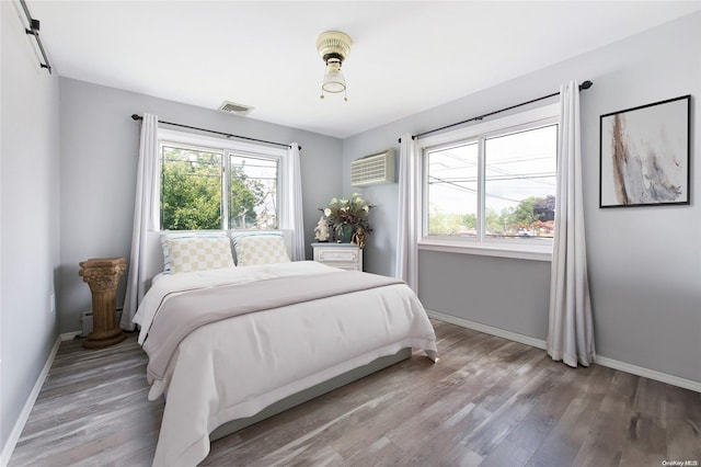 bedroom with an AC wall unit and hardwood / wood-style floors