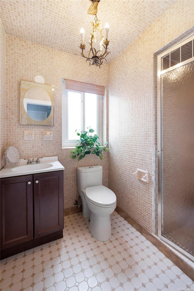 bathroom with a chandelier, vanity, a shower with shower door, and toilet