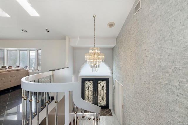 tiled foyer entrance featuring a chandelier and french doors