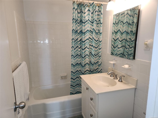 bathroom with vanity, tiled shower / bath combo, and tile walls