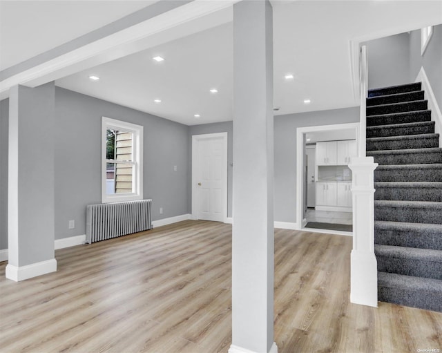 unfurnished living room featuring radiator and light wood-type flooring