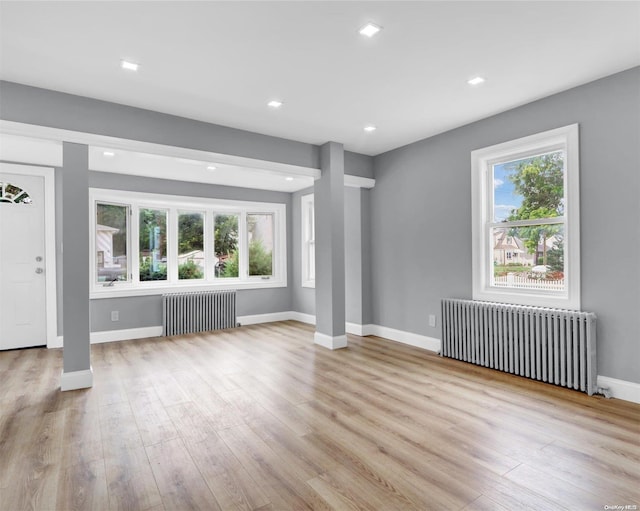 unfurnished living room with radiator heating unit and light wood-type flooring