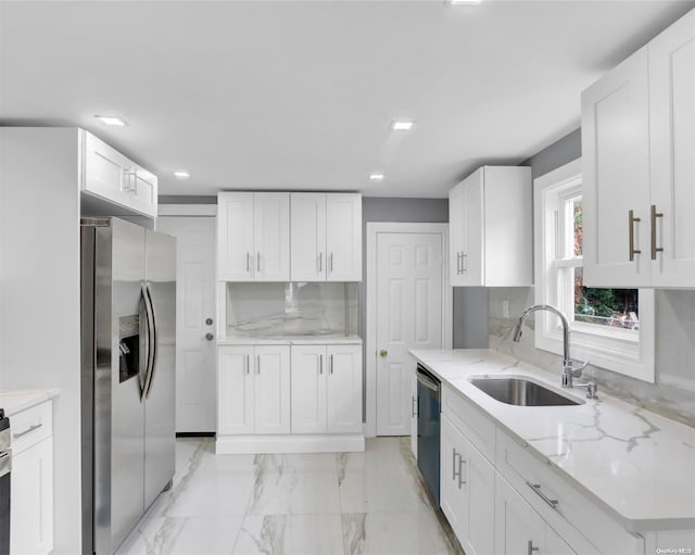 kitchen with light stone countertops, sink, white cabinets, and appliances with stainless steel finishes