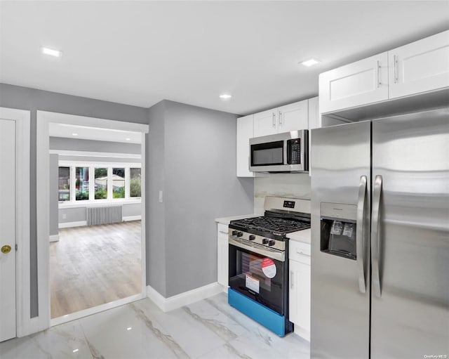 kitchen featuring white cabinetry, radiator heating unit, and appliances with stainless steel finishes