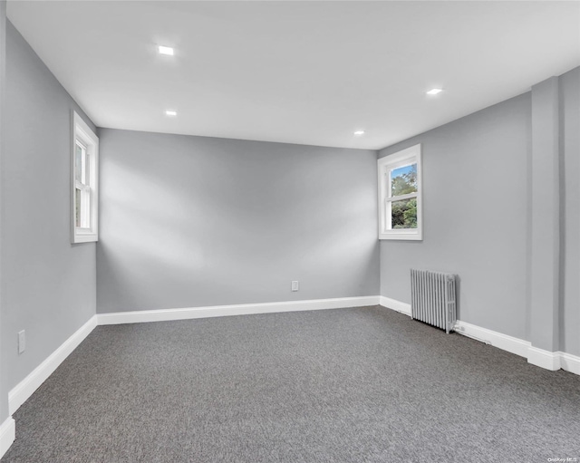 unfurnished room with dark colored carpet and radiator