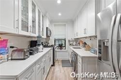 kitchen featuring sink, white cabinets, stainless steel appliances, and light wood-type flooring