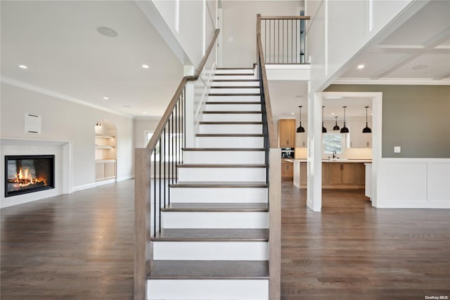 stairs with hardwood / wood-style floors, built in shelves, and crown molding