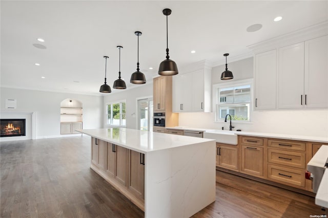 kitchen with light stone counters, dark wood-type flooring, sink, a kitchen island, and hanging light fixtures