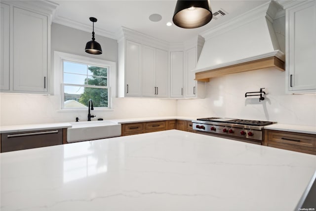 kitchen with sink, white cabinets, custom range hood, and range