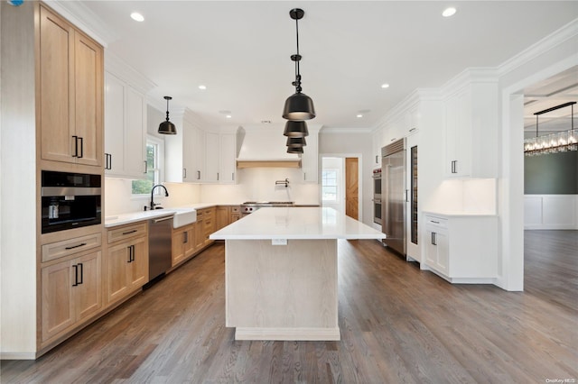 kitchen with light brown cabinets, premium range hood, ornamental molding, appliances with stainless steel finishes, and a kitchen island