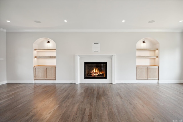 unfurnished living room featuring built in features, dark wood-type flooring, and ornamental molding