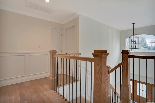 interior space with light wood-type flooring, ornamental molding, and an inviting chandelier