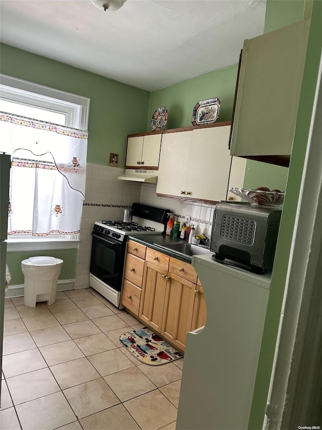 kitchen featuring white range with gas cooktop, decorative backsplash, sink, and light tile patterned flooring