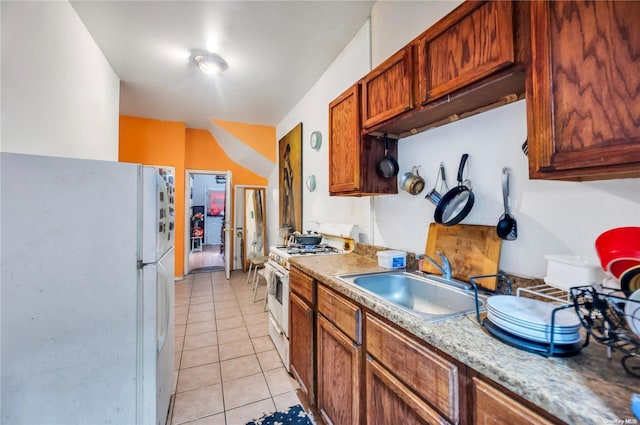 kitchen featuring light tile patterned flooring, white appliances, and sink