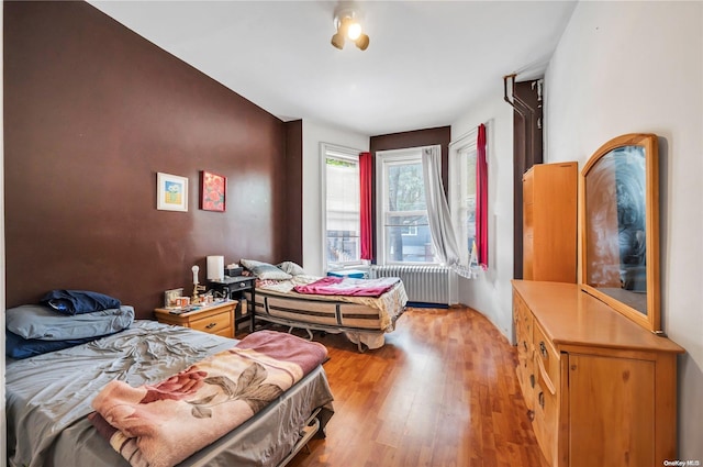 bedroom featuring radiator heating unit and light wood-type flooring