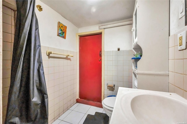 bathroom featuring tile patterned flooring, toilet, and tile walls