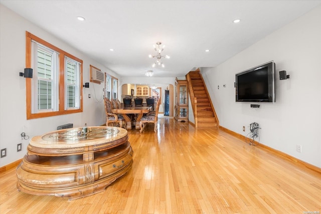 living room featuring light hardwood / wood-style flooring, a chandelier, and a wall mounted air conditioner