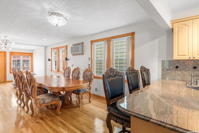 dining room featuring a notable chandelier, a textured ceiling, and light hardwood / wood-style flooring