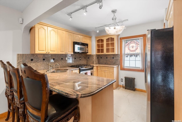 kitchen featuring radiator, sink, kitchen peninsula, decorative backsplash, and appliances with stainless steel finishes