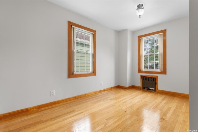 empty room featuring radiator heating unit and light wood-type flooring