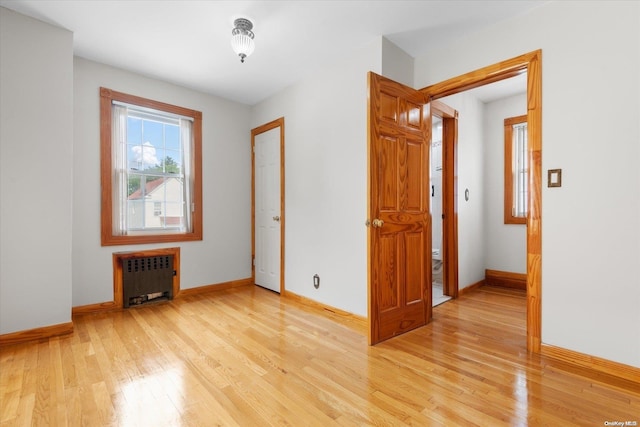 spare room featuring radiator and light hardwood / wood-style flooring