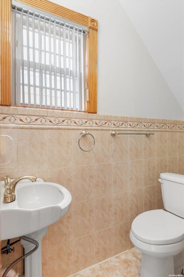 bathroom featuring tile patterned floors, toilet, and tile walls